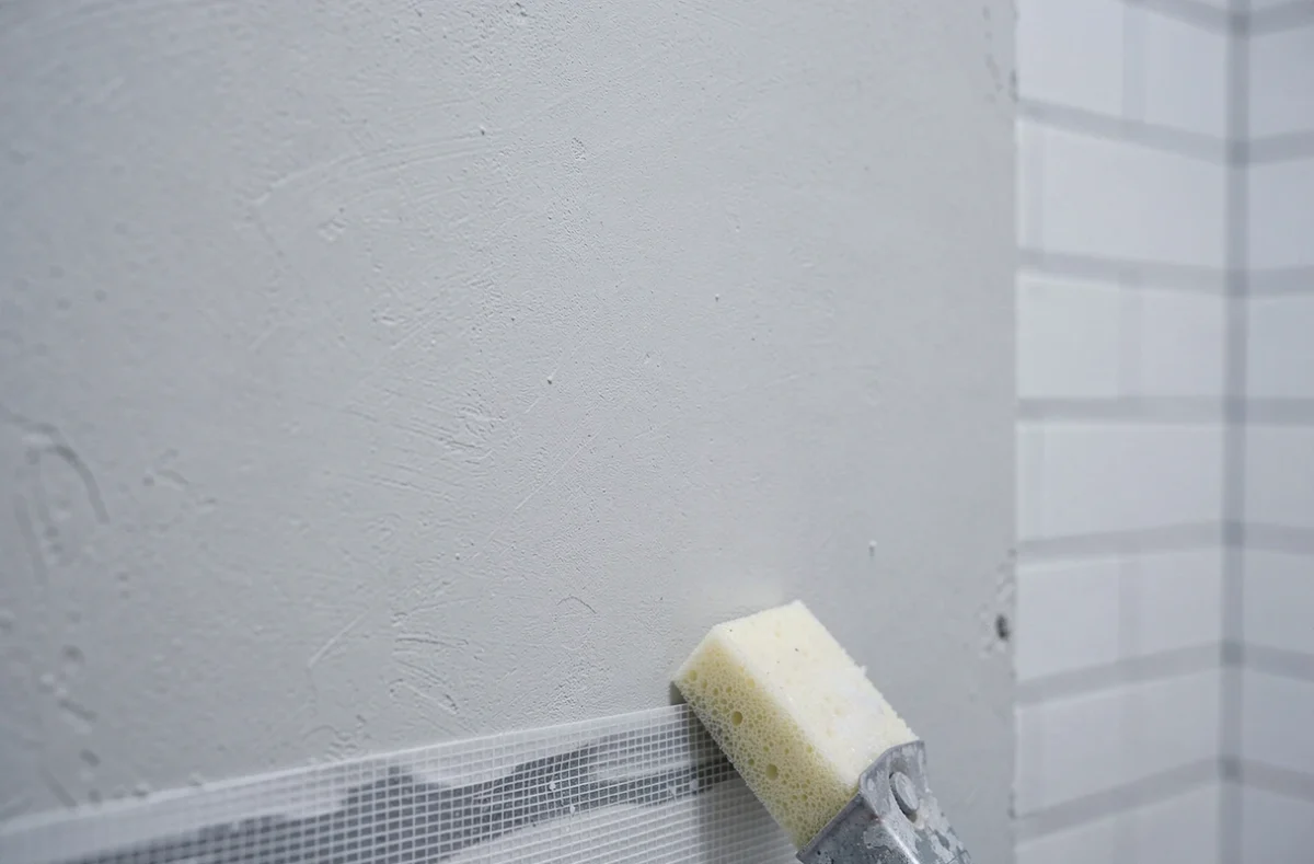 Gros plan sur une surface d'enduit MAP séché sans fissures ni reprises dans une salle de bain en rénovation