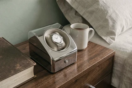 Remontoir automatique silencieux posé sur une table de nuit en noyer avec une montre habillée argentée dans une chambre minimaliste