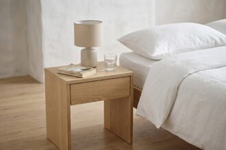 Table de nuit en bois minimaliste avec livre et verre d'eau dans une chambre épurée aux tons neutres